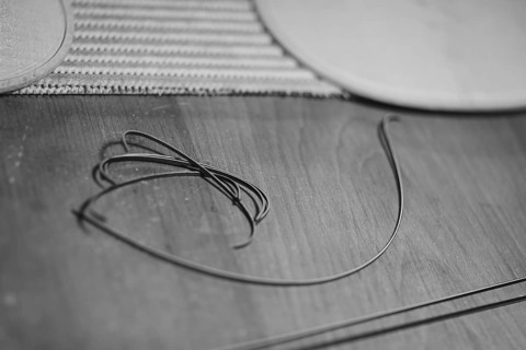 Front and back plates of new raw handmade classic violin on a workbench in violinmaker artisan workshop and purfling fillet made of evony and ivory or pear wood ready to be inserted in the carved all ...