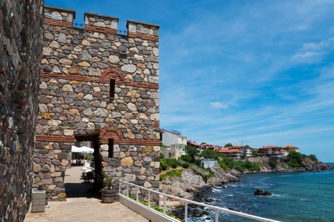 Ancient stone tower on a rocky coast with clear blue sky and calm sea