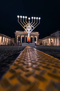 Menorah in front of the Brandenburg Gate at night with festive lighting