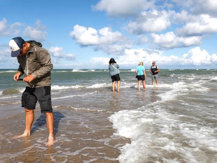 Tourists stand with one foot in the North Sea and one in the Baltic Sea in Grenen or Skagens Gren