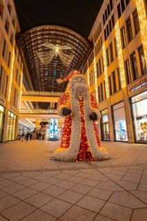 Pedestrian zone at night with a large illuminated Father Christmas and decorated shops