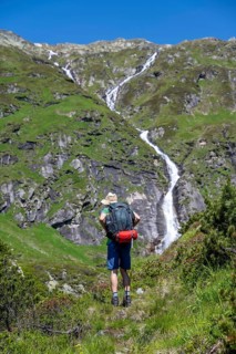 Mountaineer in front of a waterfall, Berliner Hoehenweg, Zillertal Alps, Tyrol, Austria, Europe