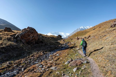 Hikers in the Achik-Tash valley, snow-covered mountain peak Pik Lenin in the background, Trans Alay