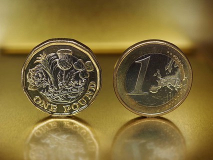 1 pound and 1 euro coin over metal background