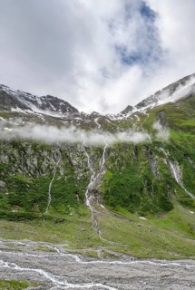 Mountain streams flow over steep mountain slopes into the Schlegeisgrund valley, cloudy rocky