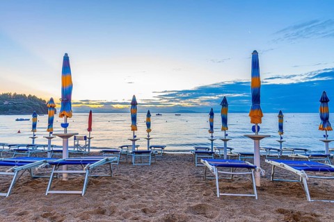 Sun loungers and parasols on Straccolignino beach at sunrise, near Capoliveri, Elba, Tuscan