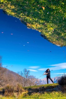Male Golfer Reflected in a Water Pond and Hitting the Golf Ball on Fairway on Golf Course with
