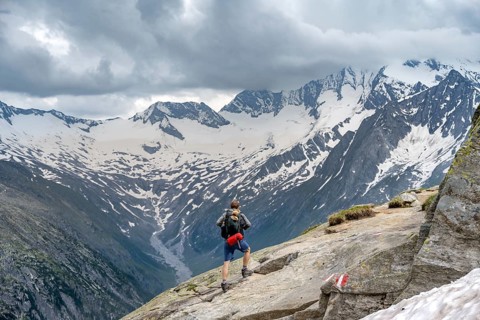 Mountaineer on hiking trail, view of glaciated rocky mountain peaks Hoher Weisszint and Hochfeiler