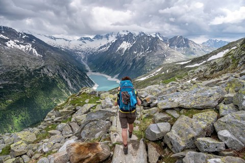Mountaineer on hiking trail, view of Schlegeisspeicher, glaciated rocky mountain peaks Hoher