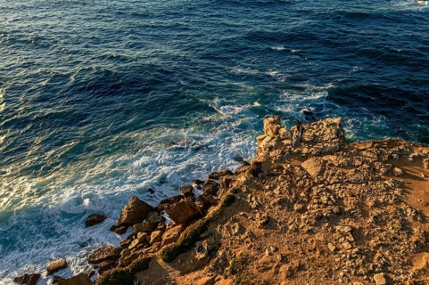 Aerial landscape of rocky shores and blue ocean waves. Drone shot of sea blue waves beat and splash