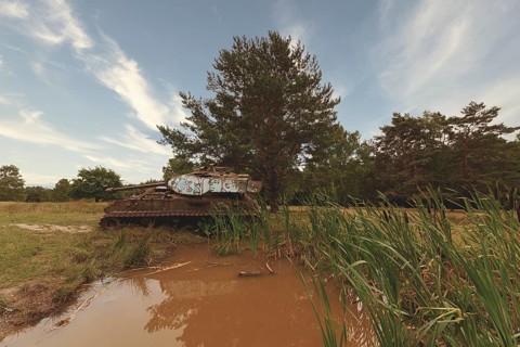 Abandoned tank stands in the middle of nature, silently reflected in the water of a pond, M41