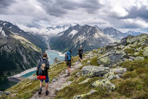 Mountaineer on hiking trail, view of Schlegeisspeicher, glaciated rocky mountain peaks Hoher