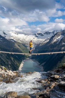Mountaineers on a suspension bridge over a mountain stream Alelebach, picturesque mountain