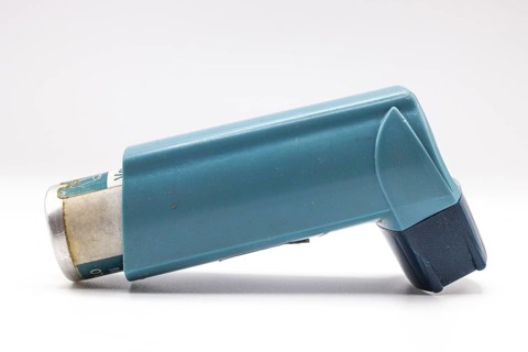 Blue asthma inhaler with blank label isolated on white background. Pharmaceutical product is used
