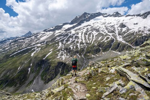 Mountaineer on rocky hiking trail, Berliner Hoehenweg, mountain landscape with snow-covered peak