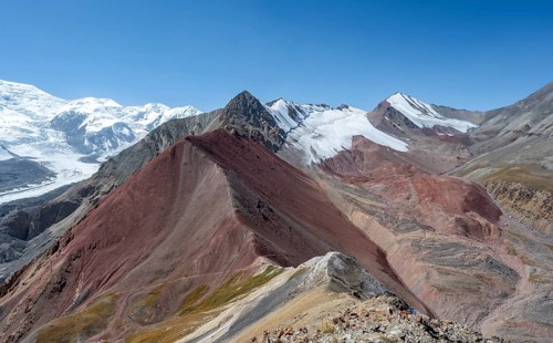 Mountain landscape of glacial moraines, mountains with red and yellow rocks, glaciated mountains in