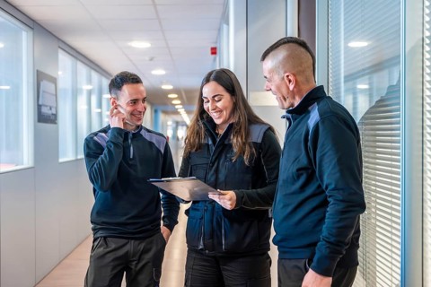 Workers of a logistic factory talking in a corridor holding a folder with paperwork