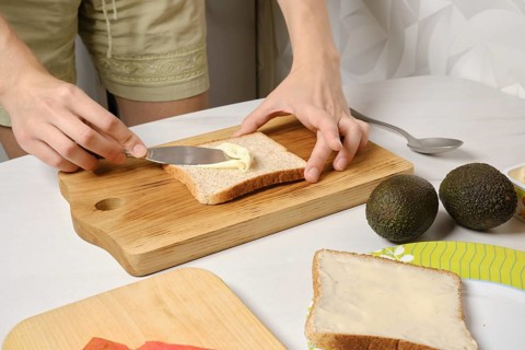 Hands of woman spreading soft cheese on toast