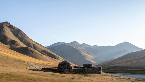 Historic caravanserai Tash Rabat from the 15th century, in the evening light with golden hills,
