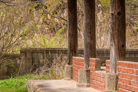Inside view of old oriental style covered pavilion surrounded by a concrete wall in an overgrown