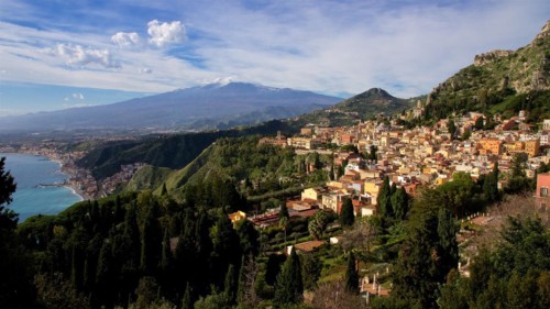 Mount Etna, panoramic view of a coastal town with mountains in the background and clear sky,