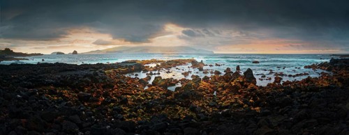 Panoramic coastal view of the town of Madalena at sunset with rocky volcanic and the island of
