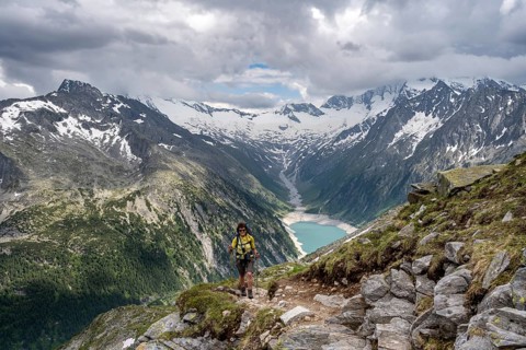 Mountaineer on hiking trail, view of Schlegeisspeicher, glaciated rocky mountain peaks Hoher