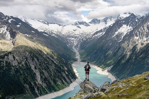 Mountaineer on a rock in front of a mountain panorama, view of Schlegeisspeicher, glaciated rocky