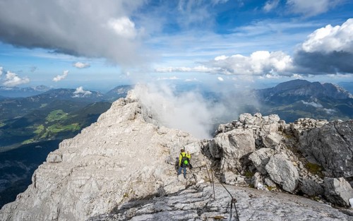 Climber on a via ferrata secured with steel rope, narrow rocky ridge, Watzmann crossing to Watzmann