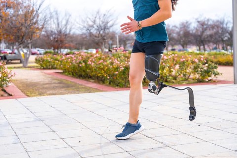 Side view of the lower part of a disabled person with prosthetic leg running in an urban park