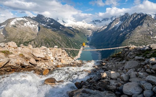 Mountaineers on a suspension bridge over a mountain stream Alelebach, picturesque mountain