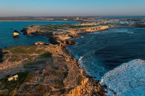 Sunset landscape of peninsula, bay and town of Peniche, Portugal. Summer sunset haze, little