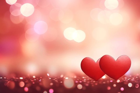 A beautiful and romantic background featuring two elegant red hearts against a soft, bokeh light