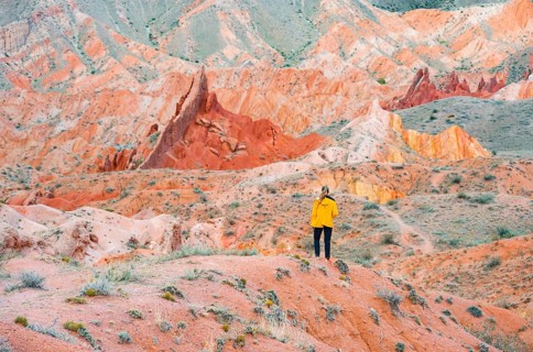 Hiker in front of eroded mountain landscape, sandstone cliffs, canyon with red and orange rock