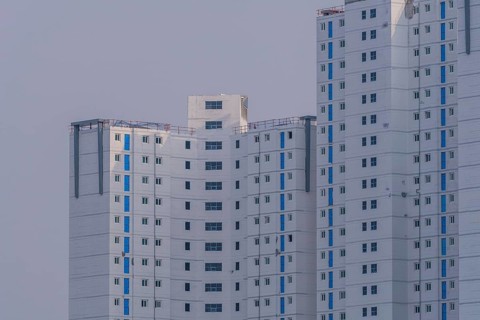 New highrise apartments with unfinished white concrete exterior walls and blue coverings on widow