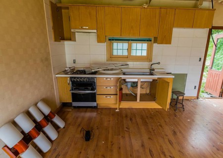 Kitchen area of abandoned house with dirt and electrical fixtures debris on counter top and leaning