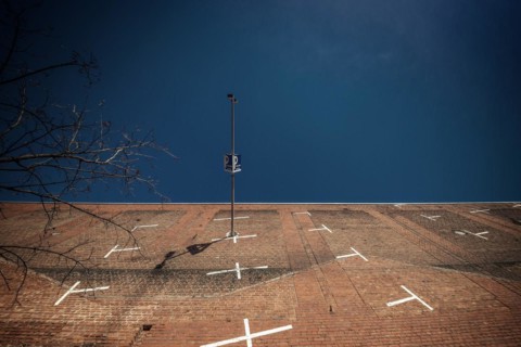 A lamppost and a car park sign in front of a brick wall with white lines, Cologne Deutz, North