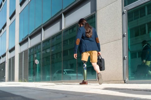 Rear view photo with copy space of a businessman with amputee leg walking along a financial