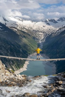 Mountaineers on a suspension bridge over a mountain stream Alelebach, picturesque mountain