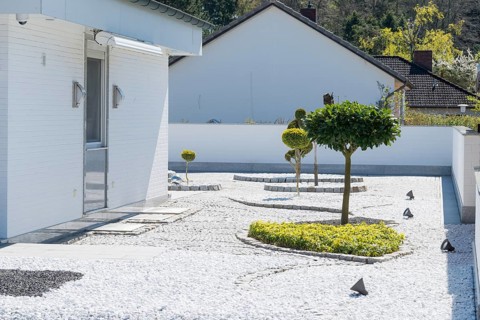 Modern garden with geometric shapes and spotlights next to a white house, residential design in