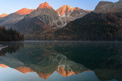 Mountains reflected in a mountain lake at sunrise, autumn, Lake Antholz, Rieserferner Group, South