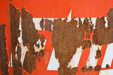 Rusty surface with peeling red paint and white stripes, weathering, symbol of decay, vacancy, need