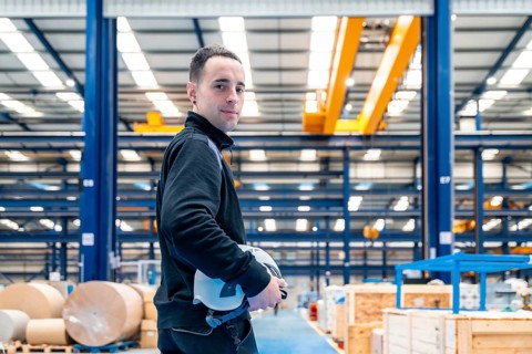 Worker turning to smile at camera standing proud in a logistic center