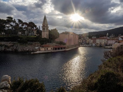 Morning sun breaking through clouds, view of the harbour entrance of Veli Losinj, with St.