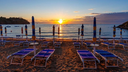 Sun loungers and parasols on Straccolignino beach at sunrise, near Capoliveri, Elba, Tuscan