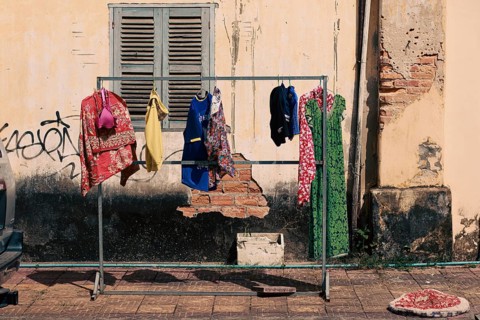 Laundry hung to dry outside in front of a weathered wall on the street side of Kampot Cambodia,