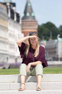 Swedish woman sitting on the steps in Angfaerjepark at the Kajpromenaden, portrait, behind the town