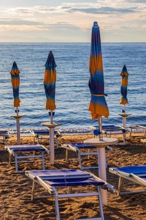 Sun loungers and parasols on Straccolignino beach at sunrise, near Capoliveri, Elba, Tuscan