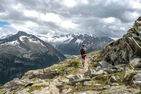 Mountaineer on hiking trail with snow, Berliner Hoehenweg, mountain landscape with glaciated peaks