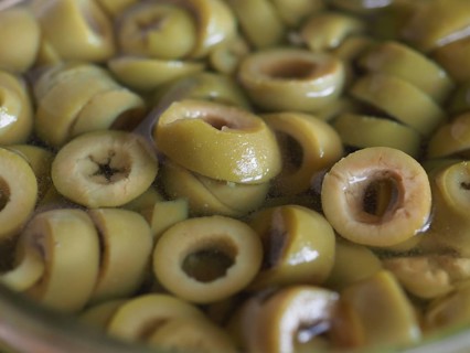 Sliced green olives in brine background